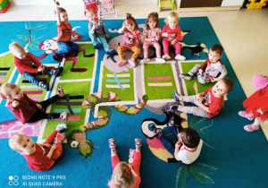 Fotografia siedzących na dywanie dzieci, trzymających lizaki w kształcie serduszka.